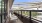a deck with a bench and a railing with a view of trees and a bridge